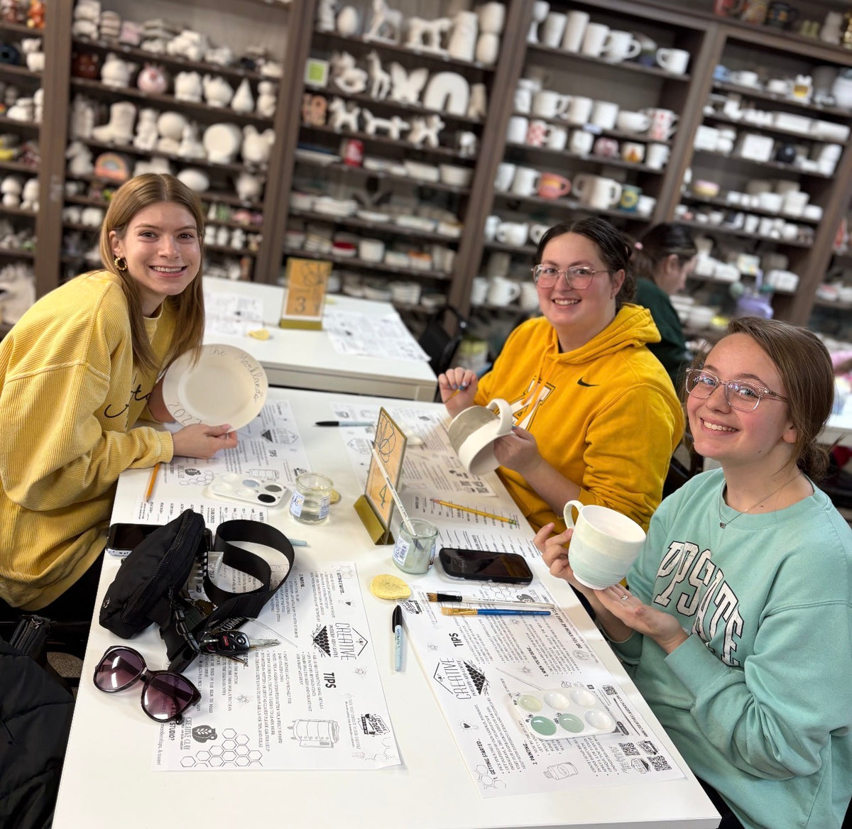Friends painting mugs and plates at CREATIVE paint-your-own pottery studio in Claremont, NC